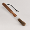 Coffee grinder dusting brush with wooden handle, hanging cord and long bristles — warm grey background