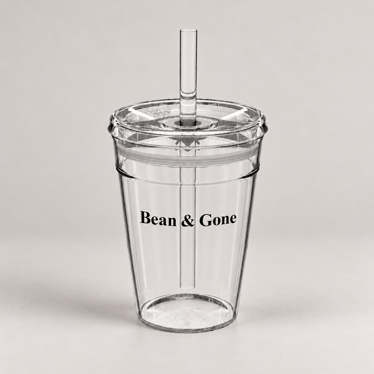 Bean & Gone Reusable Iced Coffee Cup — Black 12oz with Hard Plastic Straw on a warm grey background