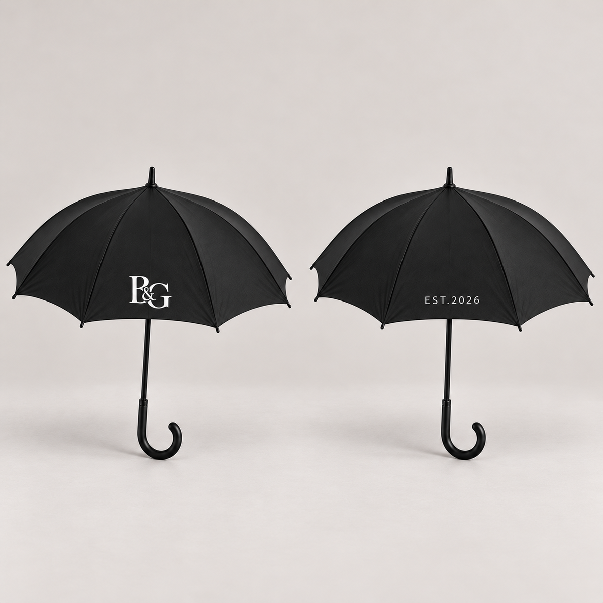 Two views of the same umbrella showing the white B&G monogram and EST.2026 on opposite sides. Design mockup; sold individually.